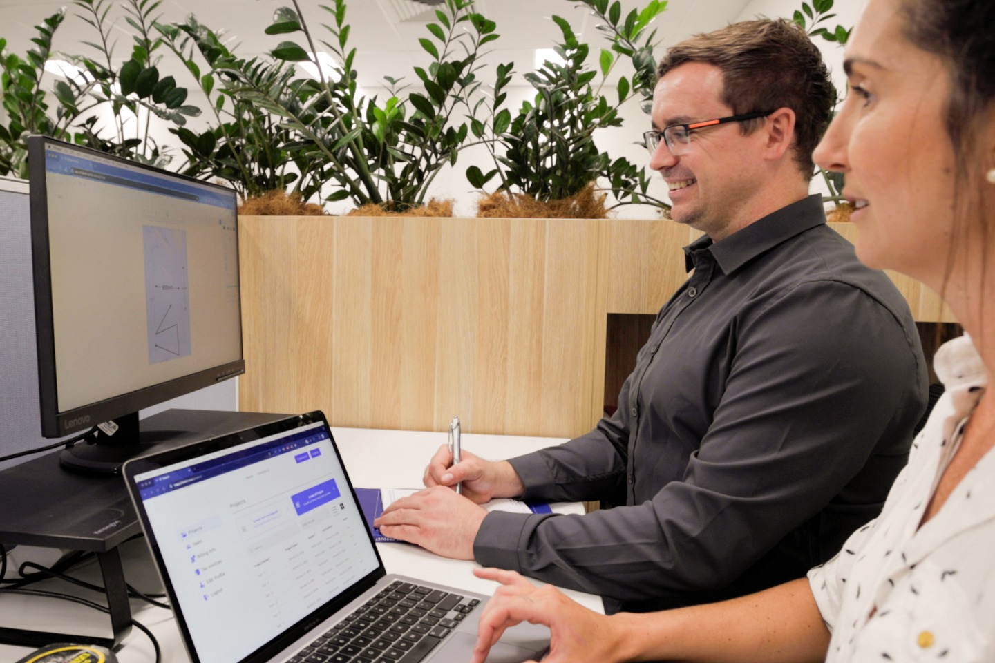 Two people using Moddy OT drawing software on a laptop and monitor in an office setting