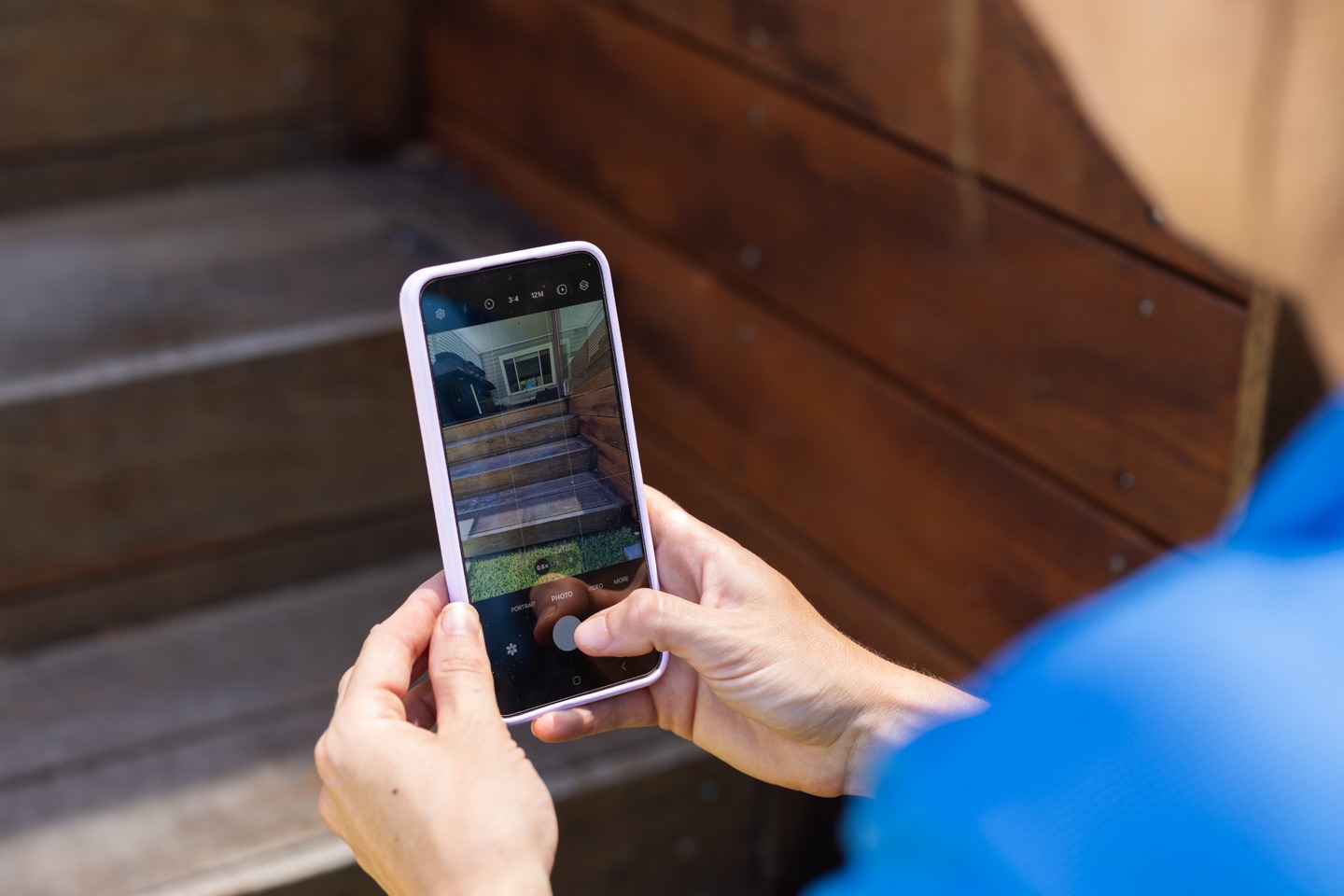 Close-up of a person taking a photo of wooden steps with a smartphone