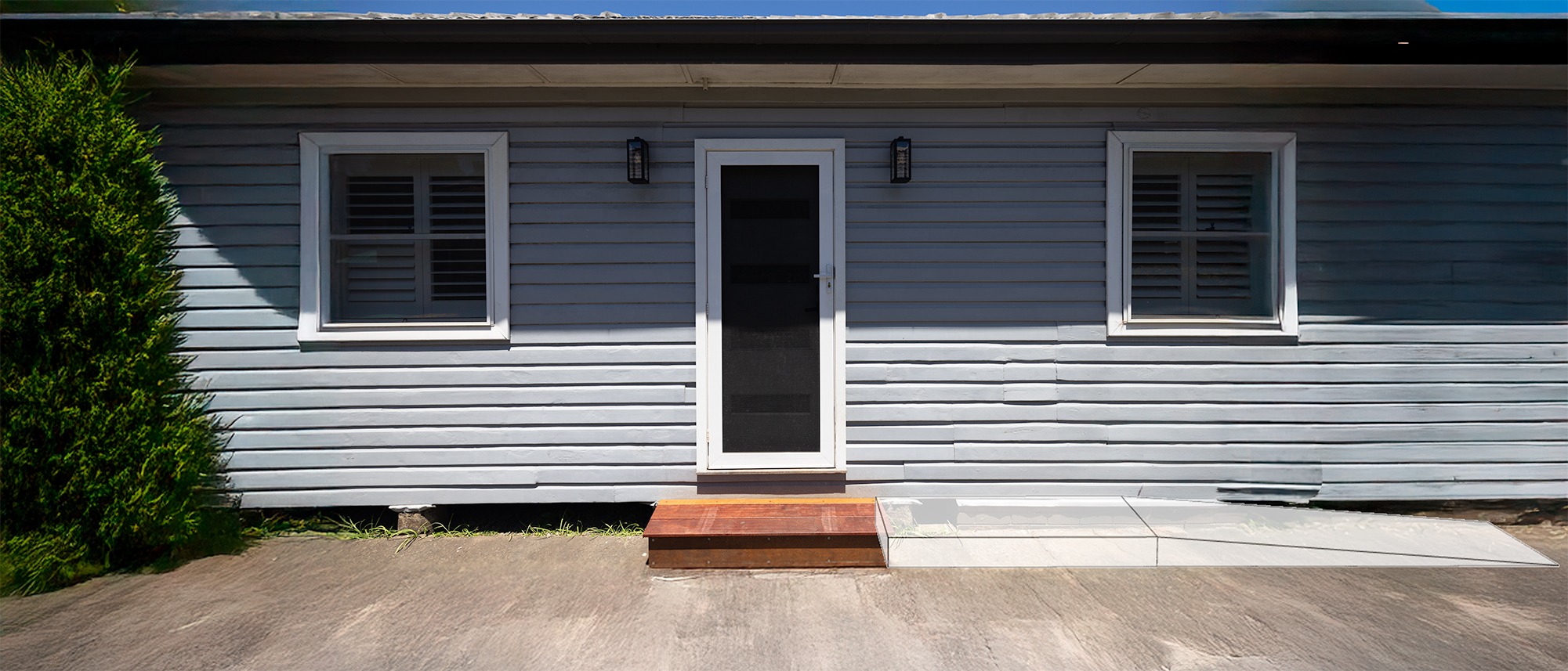 Grey house with a wooden step at the door and a translucent ramp overlay extending to the right.